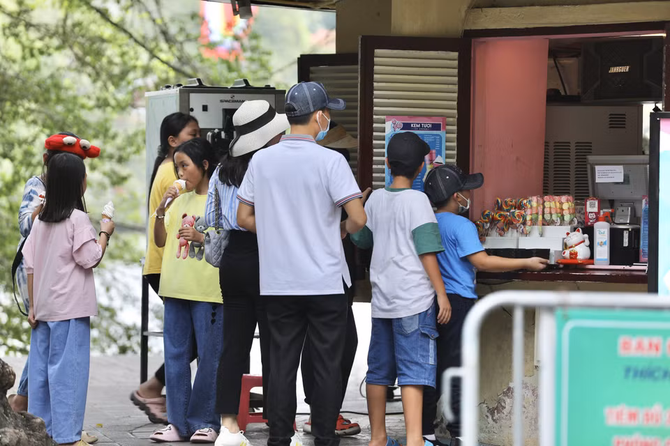 Nhiều người dân lựa chọn ăn kem, uống nước tại các cửa hàng giải khát khu vực Hồ Gươm để giải nhiệt trong ngày nắng nóng. (Ảnh: Hoàng Hiếu/TTXVN)