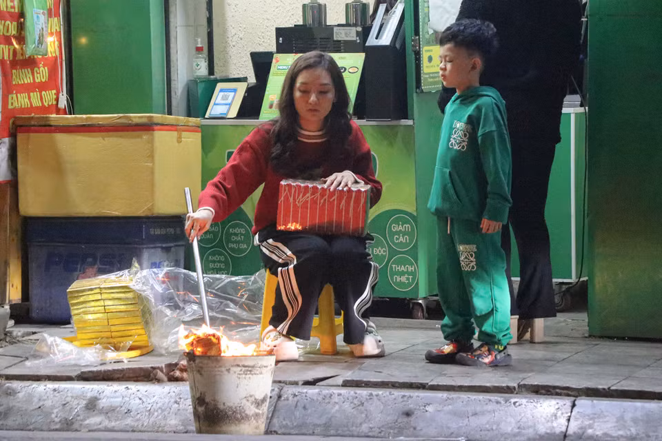 Một số gia đình tranh thủ thời gian trước giao thừa để thực hiện nghi lễ hóa vàng. (Ảnh: Việt Anh/Vietnam+)
