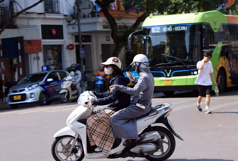 Người dân ra đường dưới cái nóng gay gắt bắt buộc che kín mít, bảo vệ sức khỏe bản thân. (Ảnh: Tuấn Anh/TTXVN)