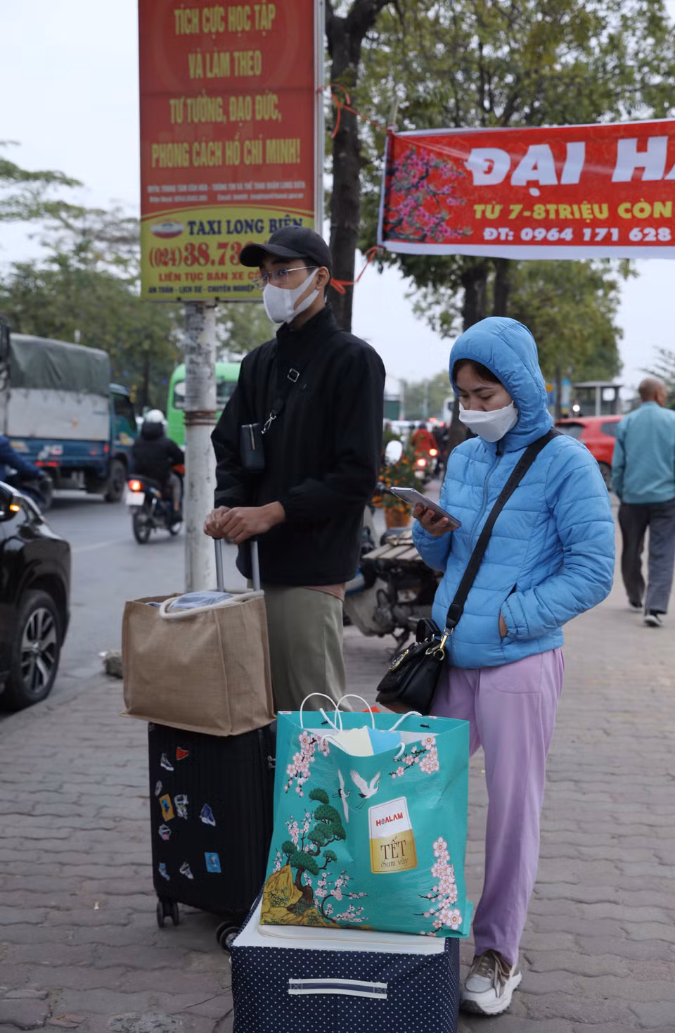 Người dân với vali, túi xách đang chờ đón xe rời Hà Nội tại đường Cổ Linh. (Ảnh: Hoàng Hiếu/TTXVN)