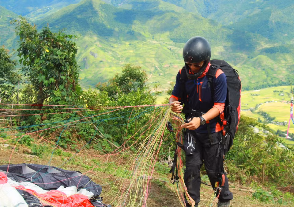 Một phi công kiểm tra dây dù trước khi bay. (Ảnh: Xuân Mai/Vietnam+)