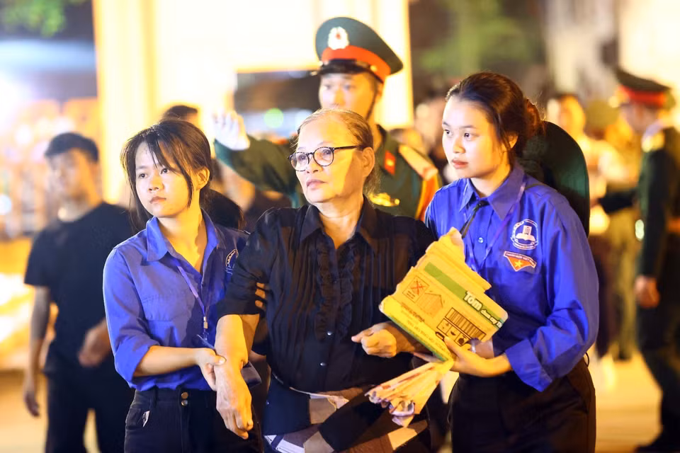 Một người dân được lực lượng thanh niên hỗ trợ đưa vào viếng Tổng Bí thư. (Ảnh: TTXVN)