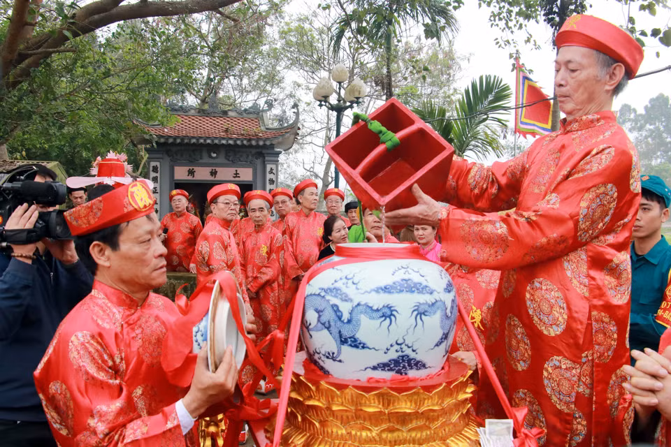 Các cụ cao niên thực hiện nghi thức lấy nước từ giếng rồng. (Ảnh: Nguyễn Lành/TTXVN)