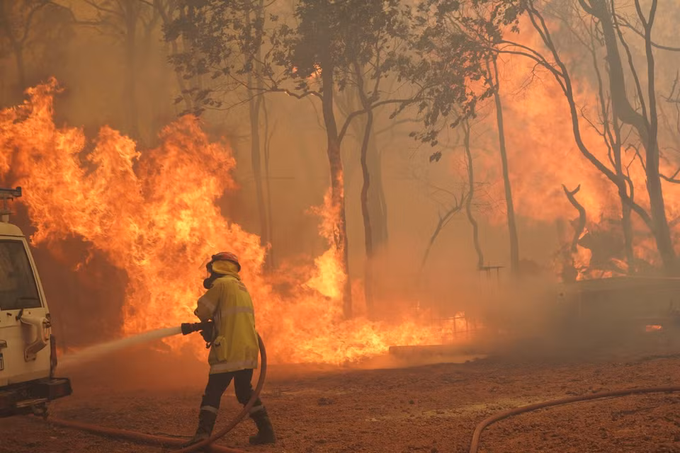  Lực lượng cứu hỏa phun nước dập lửa cháy rừng tại khu vực ngoại ô Wooroloo, gần thành phố Perth, Australia, ngày 2/2/2021. (Ảnh: AFP/TTXVN)