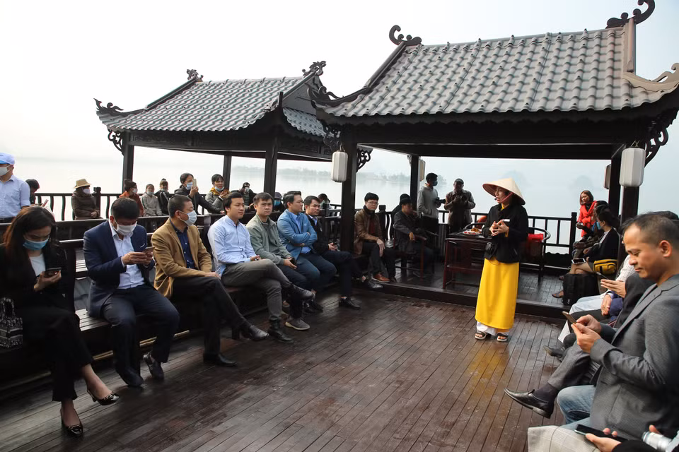 Du khách thích thú vừa trải nghiệm đi thuyền trên đầm vừa nghe hướng dẫn viên giới thiệu về sự tích và kiến trúc chùa Tam Chúc. (Ảnh: Xuân Mai/Vietnam+)