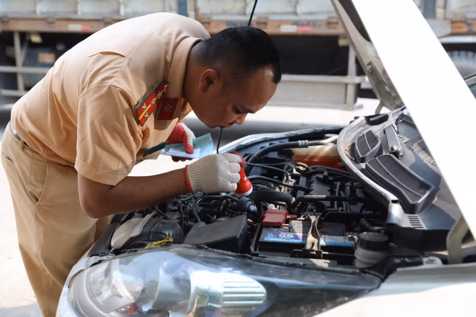 Đại úy công an Đinh Văn Toàn (PC08 Hưng Yên) kiểm tra số máy của xe đến đăng kiểm sáng 14/3. (Ảnh: Hoàng Hiếu/TTXVN)