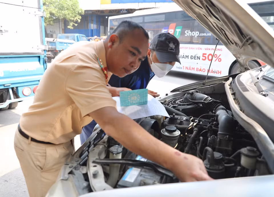 Đại úy công an Đinh Văn Toàn (PC08 Hưng Yên) kiểm tra số khung, số máy của xe đến đăng kiểm tại Trung tâm đăng kiểm xe cơ giới 2906V. (Ảnh: Hoàng Hiếu/TTXVN)