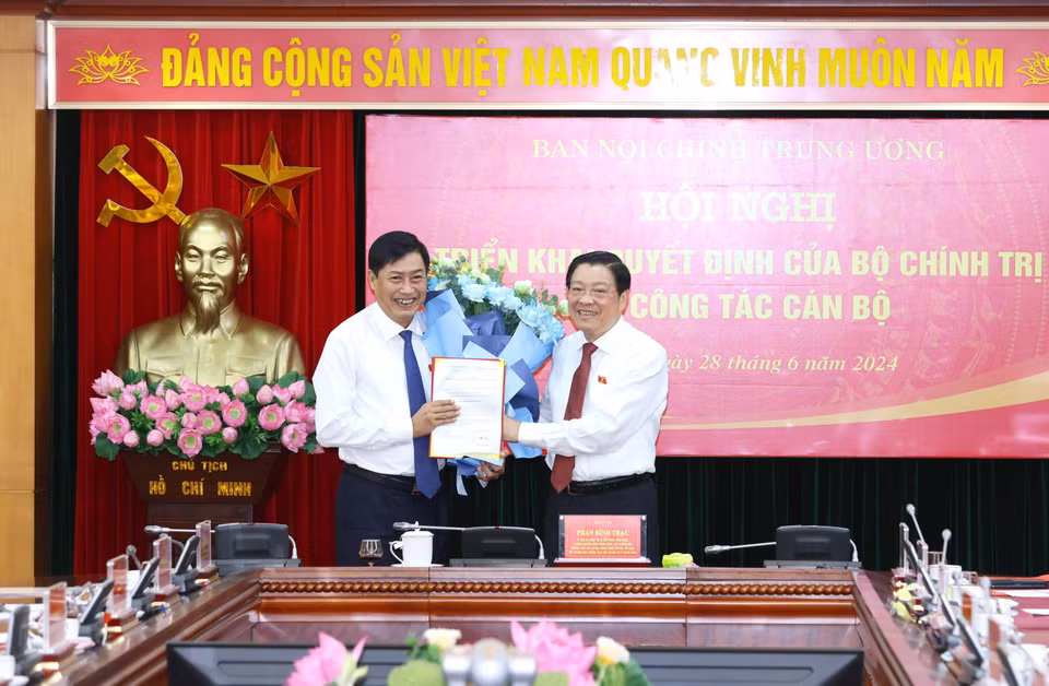 Ông Phan Đình Trạc, Ủy viên Bộ Chính trị, Bí thư Trung ương Đảng, Trưởng Ban Nội chính Trung ương trao Quyết định của Bộ Chính trị cho ông Nguyễn Hữu Đông. (Ảnh: Phương Hoa/TTXVN)