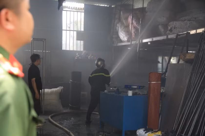 Lực lượng chức năng tiến vào bên trong kho hàng để chữa cháy. (Ảnh: Nhật Anh/TTXVN)