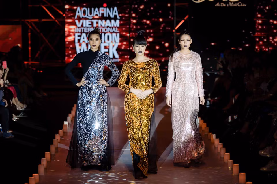 Bộ 3 người mẫu Trang Trần, Kim Dung và diễn viên Thúy Diễm uyển chuyển mở màn với trang phục áo dài đính mica gương lấp lánh. Sàn diễn với cường độ ánh sáng giảm dần càng tăng thêm tính huyền ảo cho không gian của bộ sưu tập. (Ảnh: CTV)
