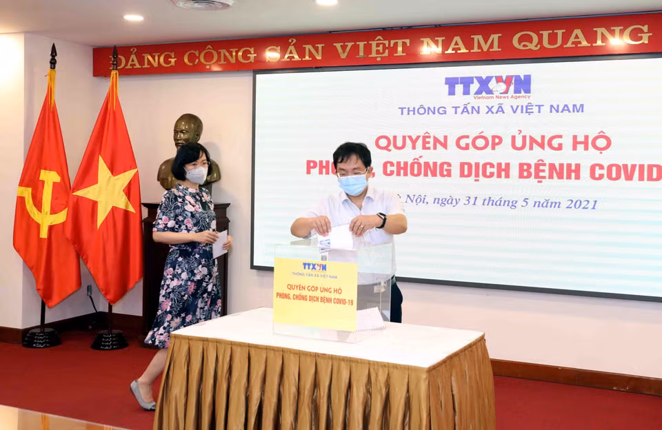 Phó Tổng Giám đốc TTXVN Nguyễn Tuấn Hùng quyên góp, ủng hộ Quỹ phòng, chống dịch COVID-19. (Ảnh: Phạm Kiên/TTXVN)