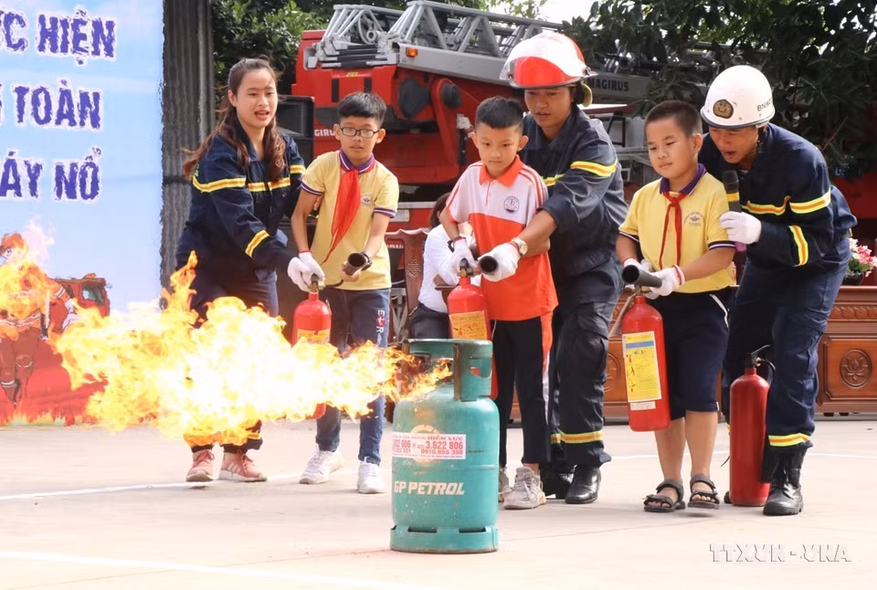 Các chiến sỹ cảnh sát phòng cháy chữa cháy tỉnh Bắc Ninh hướng dẫn học sinh trải nghiệm 'Một ngày làm lính cứu hỏa.' (Ảnh: Đinh Văn Nhiều/TTXVN)