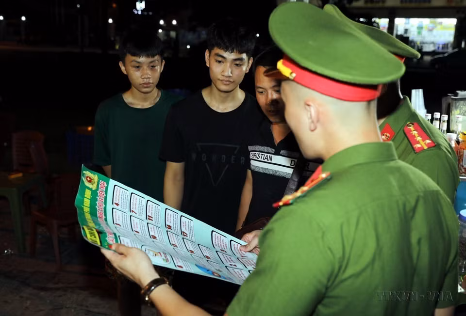 Công an thành phố Nam Định trực tiếp tuyên truyền tới người dân về việc phòng, chống lừa đảo qua mạng tại những địa điểm vui chơi buổi tối. (Ảnh: Thái Thuần/TTXVN)