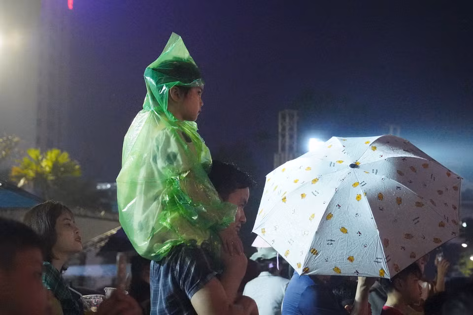 Ô dù và áo mưa là những phụ kiện giúp các bậc phụ huynh yên tâm khi đưa con em đến thưởng thức buổi bắn pháo hoa. (Ảnh: Việt Anh/Vietnam+)