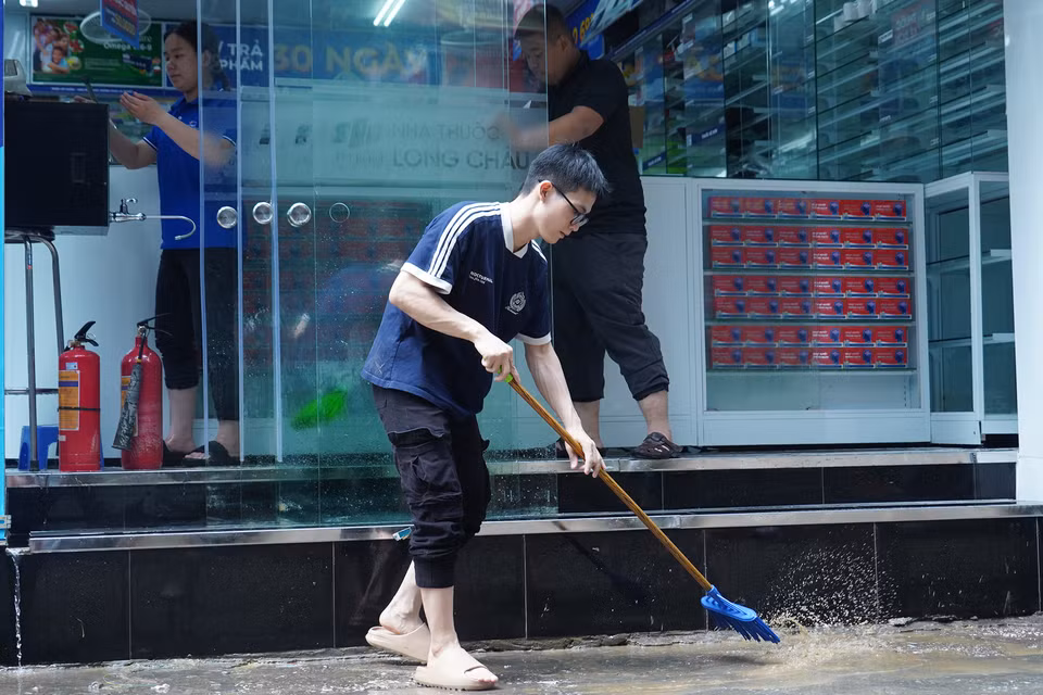Người dân dùng chổi, cọ, liên tục khuấy để nước bùn không đọng lại trong nhà cửa. (Ảnh: Việt Anh/Vietnam+)