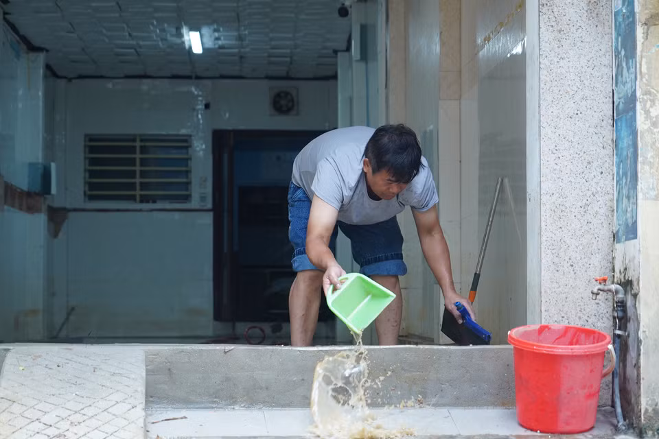 Người dân dùng cọ, chổi dọn nước bùn ra khỏi nhà. (Ảnh: Việt Anh/Vietnam+)