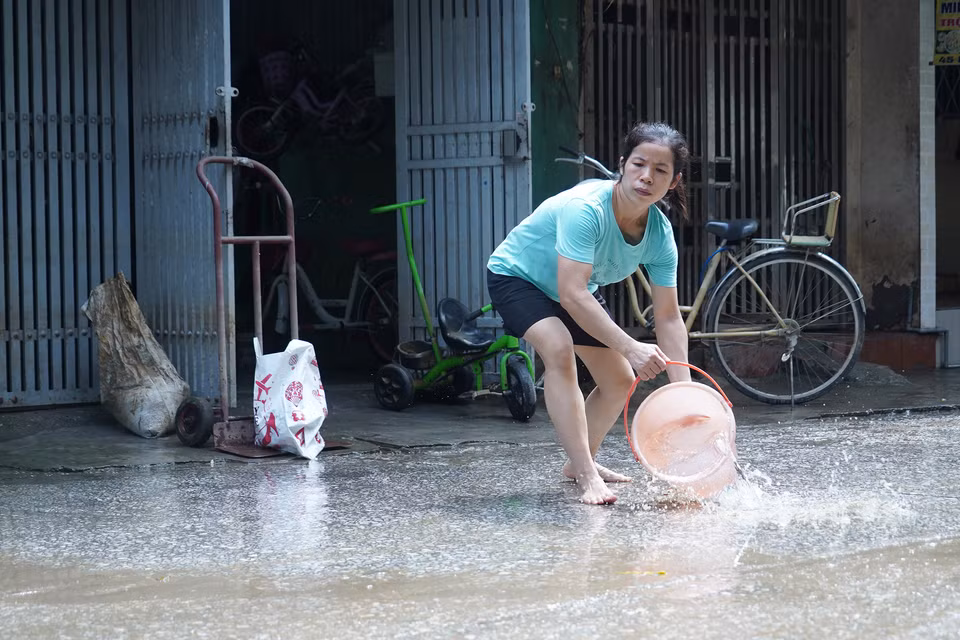 Các xô, chậu cũng được mang ra hứng nước, rửa sạch nền đường. (Ảnh: Việt Anh/Vietnam+)