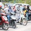 Khẩu trang, áo chống nắng là những thứ không thể thiếu của người dân khi tham gia giao thông. (Ảnh: Lê Đông/TTXVN)
