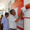 Người dân xem danh sách cử tri được niêm yết tại điểm bỏ phiếu. (Ảnh: Nhựt An/TTXVN)