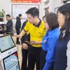 Cán bộ Trung tâm phục vụ hành chính công xã Quỹ Nhất hướng dẫn người dân thao tác trên Robot Lễ tân AI. (Ảnh: Công Luật/TTXVN)
