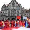 Hơn 200 chị em trong tà áo dài rực rỡ cùng lá cờ Tổ quốc tung bay giữa thành phố cổ kính Dresden (Đức). (Ảnh: Phương Hoa/TTXVN)