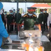 Lực lượng chức năng thực hiện lấy mẫu hài cốt liệt sỹ ở Nghĩa trang liệt sỹ xã Phước Long. (Ảnh: Tuấn Kiệt/TTXVN)