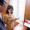 Cán bộ, chiến syc Đội Sát hạch, cấp giấy phép lái xe cơ giới đường bộ (Phòng Cảnh sát giao thông, Công an thành phố Hà Nội) hướng dẫn người dân đăng ký làm thủ tục cấp, đổi giấy phép lái xe trên Cổng dịch vụ công quốc gia và ứng dụng VNeID (ảnh chụp sáng 1/3). (Ảnh: Phạm Kiên/TTXVN)