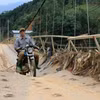 Tuy ý thức rõ ràng sự nguy hiểm, nhưng vì đây là cây cầu độc đạo nên người dân vẫn liều mình hàng ngày đi qua cầu treo này. (Ảnh: Anh Thùy/TTXVN)