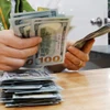 Giá bán USD trên thị trường tự do cao hơn giá bán của ngân hàng hơn 1.600 đồng/USD. (Ảnh: Vietnam+)