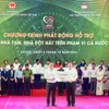 Ông Nguyễn Thanh Tùng (bên trái) - Bí thư Đảng ủy, Chủ tịch HĐQT Vietcombank trao tượng trưng kinh phí 100 tỷ đồng hỗ trợ xoá nhà tạm, nhà dột nát ủng hộ cho địa phương. (Ảnh: Vietnam+)