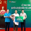 Đại diện Liên đoàn Lao động (bên trái) và đại diện công ty Cao Su Quảng Trị (bên phải) trao bảo hiểm cho người lao động. (Ảnh: Vietnam+)
