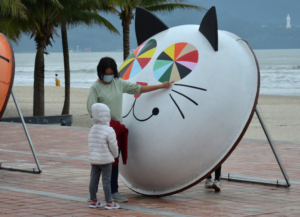 Hai mẹ con du khách và bài học về màu sắc trên “linh vật mèo” thuyền thúng. (Ảnh: Quốc Dũng/TTXVN)