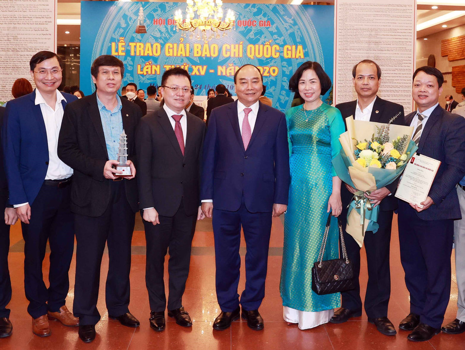 Chủ tịch nước Nguyễn Xuân Phúc, Tổng biên tập báo Nhân Dân Lê Quốc Minh và Tổng giám đốc TTXVN Vũ Việt Trang cùng các nhà báo của TTXVN. (Ảnh: Thống Nhất/TTXVN)