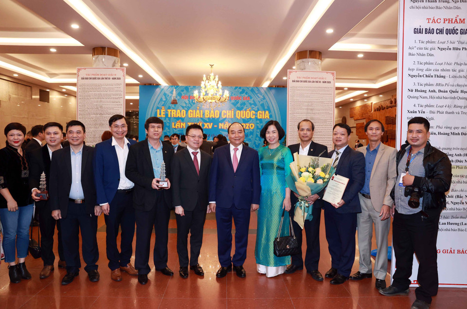 Chủ tịch nước Nguyễn Xuân Phúc, Tổng biên tập báo Nhân Dân Lê Quốc Minh và Tổng giám đốc TTXVN Vũ Việt Trang cùng các nhà báo của TTXVN. (Ảnh: Thống Nhất/TTXVN)