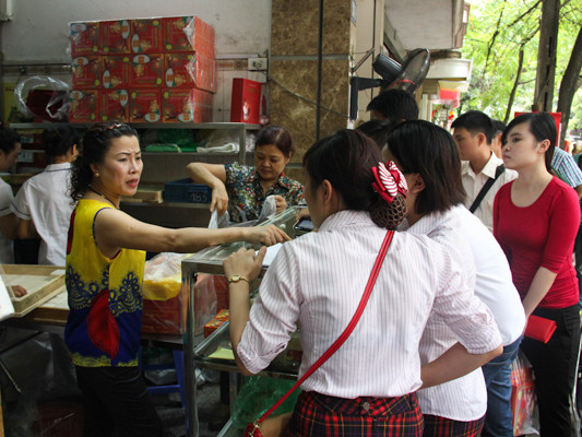 Chủ cửa hàng bánh Bảo Phương hướng dẫn người dân cách mua bánh với số lượng nhiều. (Ảnh: Minh Sơn/Vietnam+)