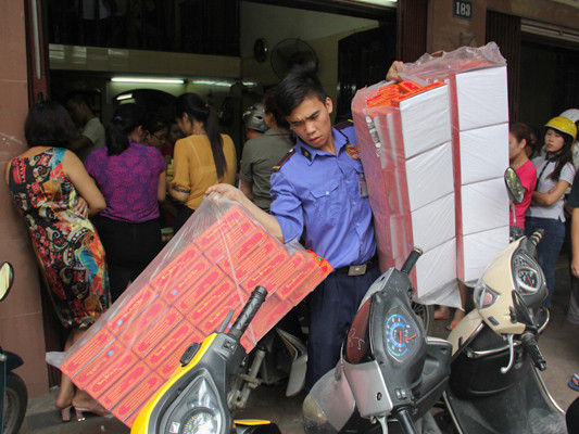 Lượng bánh làm ra không đủ cung ứng, bảo vệ kiêm luôn cả việc vận chuyển bánh cho những đơn đặt hàng trước. (Ảnh: Minh Sơn/Vietnam+)