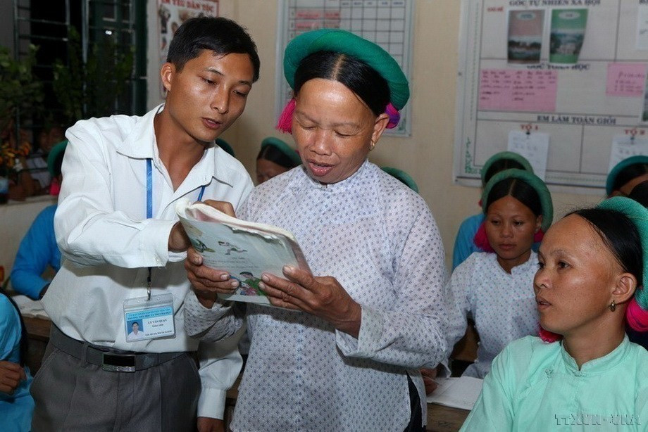 Thầy giáo tận tình hướng dẫn học viên người dân tộc tập đọc tại lớp học xoá mù chữ ở tỉnh Quảng Ninh. (Ảnh: Quý Trung/TTXVN)