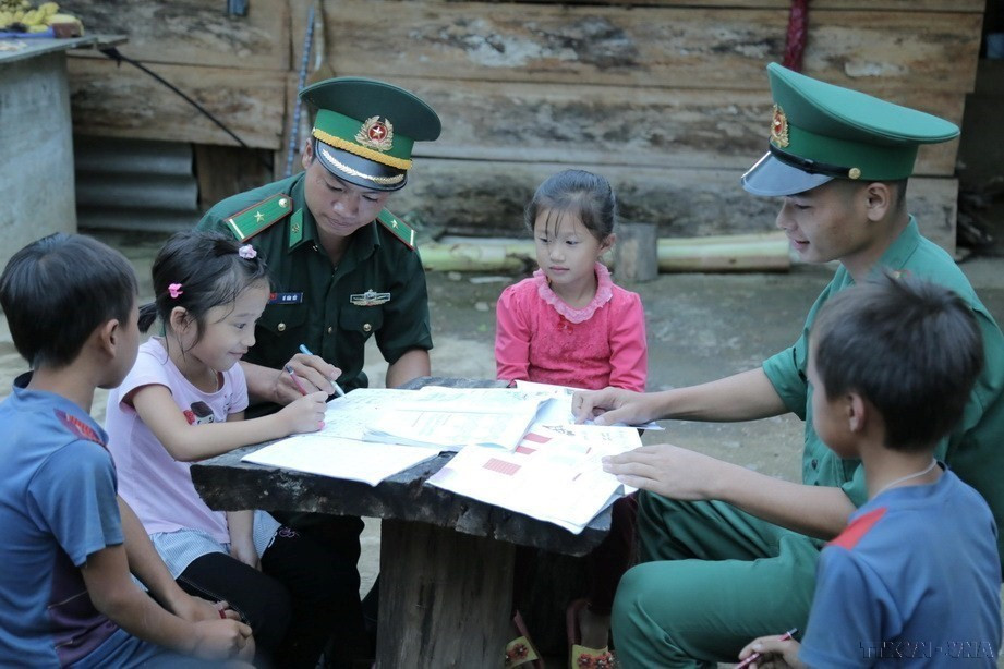 Cán bộ, chiến sỹ Đồn Biên phòng Mường Cai, tỉnh Sơn La -những thầy giáo ''mang quân hàm xanh'', hướng dẫn trẻ em vùng biên giới học bài. (Ảnh: Hữu Quyết/TTXVN)