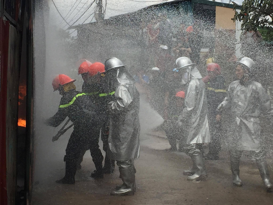 Các chiến sỹ Phòng cháy chữa cháy đã phải phá toàn bộ lớp tôn xung quanh xưởng để tiếp cận nguồn phát. (Ảnh: PV/Vietnam+) 