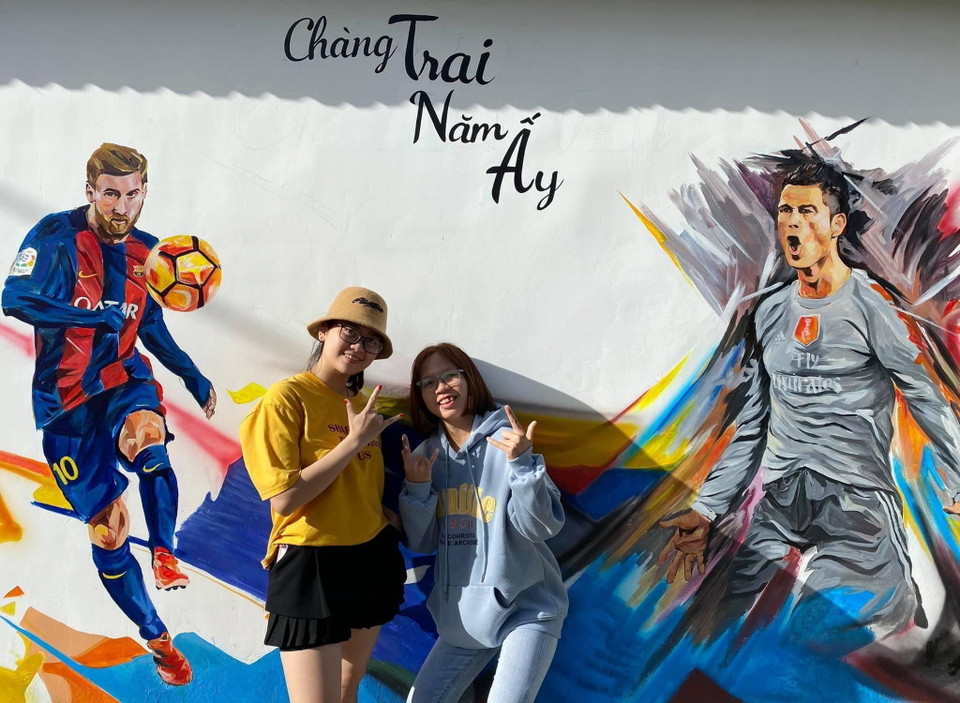 Du khách chụp ảnh lưu niệm với các bức bích họa. (Ảnh: TTXVN phát)