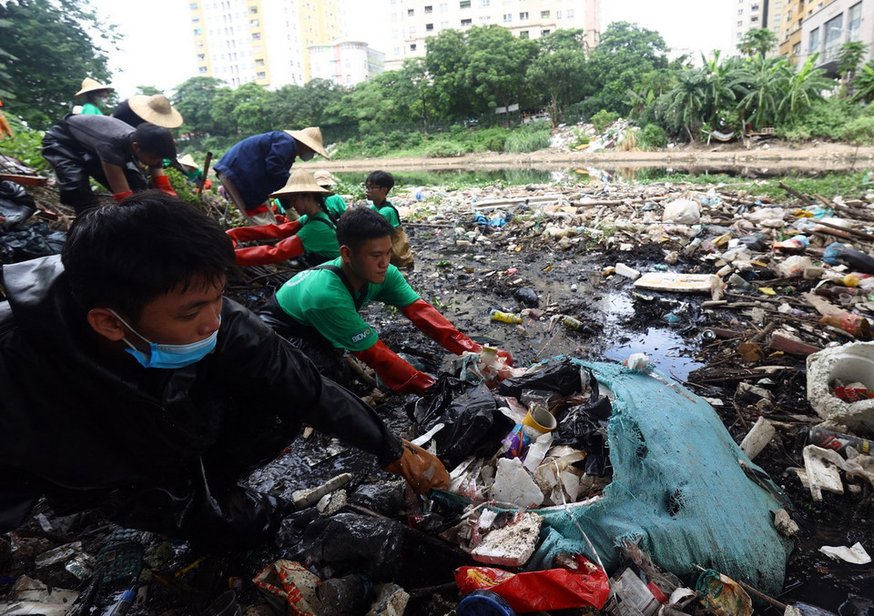 Nhiều túi rác to do người dân vứt xuống sông khiến các tình nguyện viên rất vất vả để kéo lên. (Ảnh: Tuấn Anh/TTXVN)