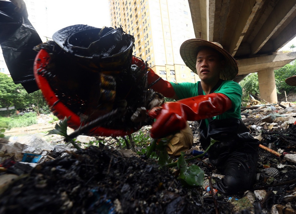 Từng đống rác to dưới sông được các tình nguyện viên lần lượt vớt lên, gom vào nhiều túi để vận chuyển đến nơi tập kết. (Ảnh: Tuấn Anh/TTXVN)