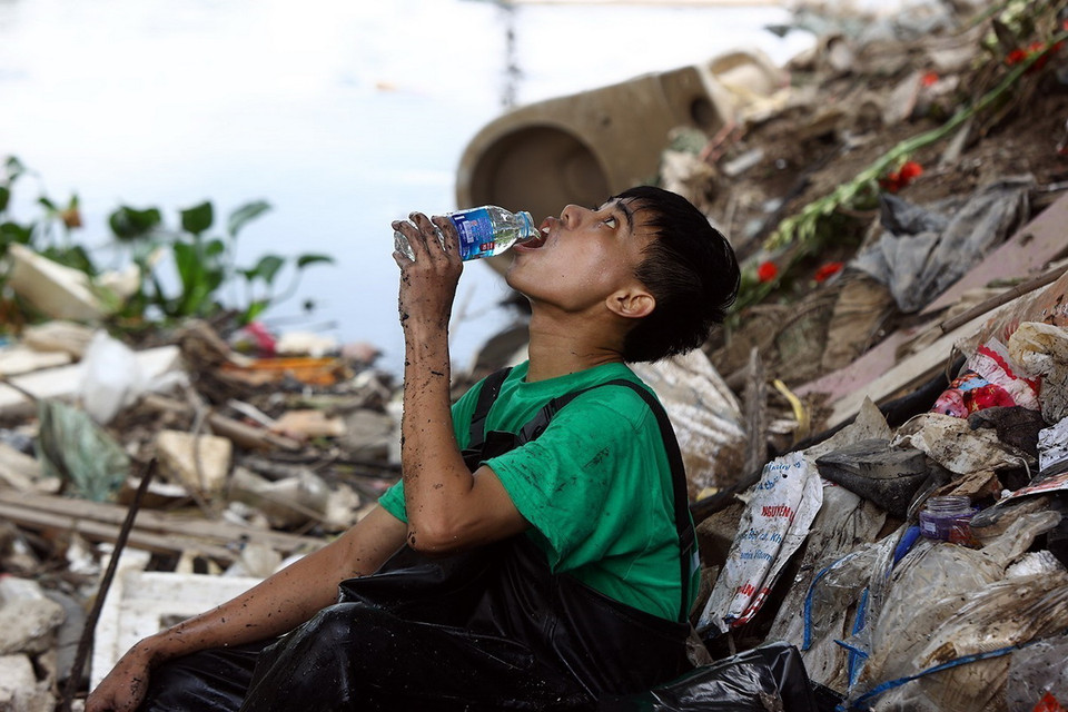 Phút nghỉ ngơi sau mấy giờ đồng hồ dầm mình gom rác dưới sông "đen". (Ảnh: Tuấn Anh/TTXVN)