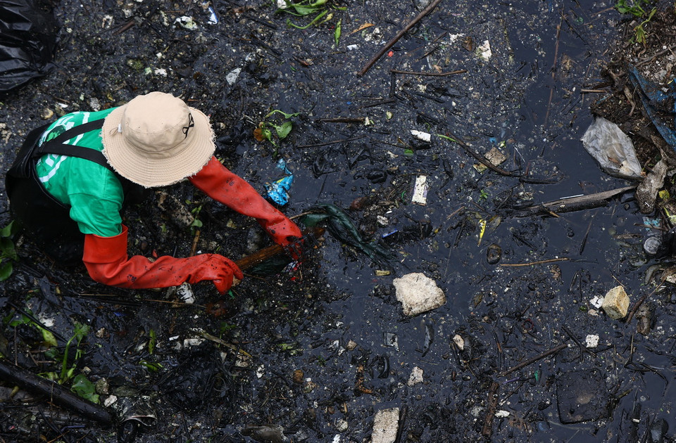 Dầm mình dưới sông "đen" để vớt rác. (Ảnh: Tuấn Anh/TTXVN)