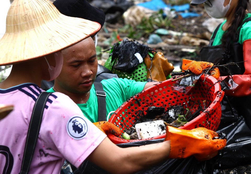 Các thành viên phải dùng rổ vớt rác dưới sông, sau đó cho vào túi nilon để đem đến nơi tập kết. (Ảnh: Tuấn Anh/TTXVN)