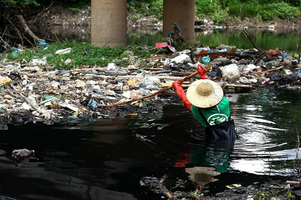 Dầm mình vớt rác, làm sạch môi trường dòng sông. (Ảnh: Tuấn Anh/TTXVN)