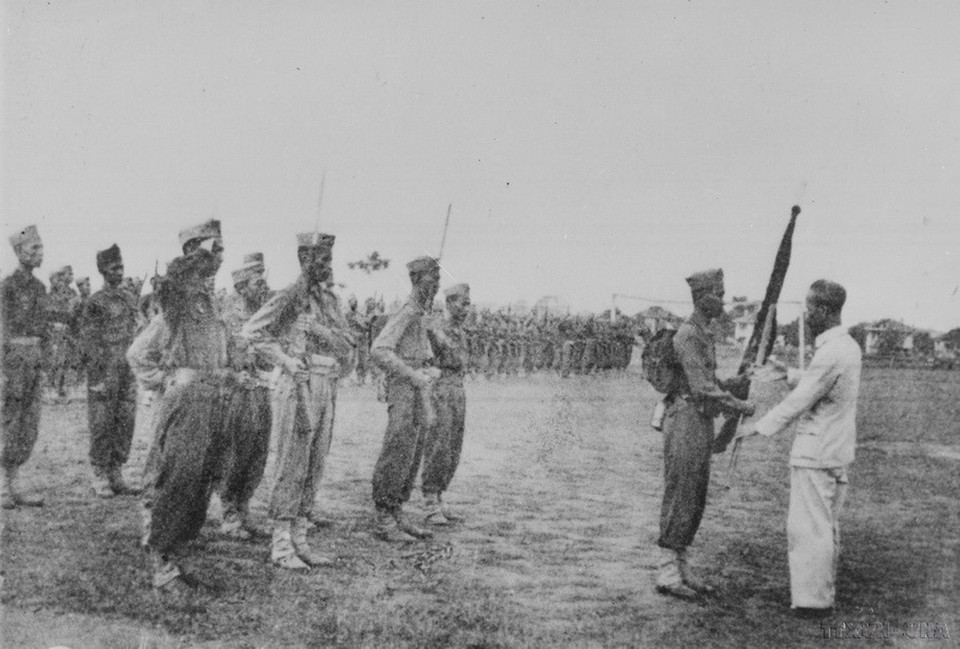 Chú tịch Hồ Chí Minh trao cờ thêu dòng chữ “Trung với nước, hiếu với dân” cho học viên khóa I trường Lục quân Trần Quốc Tuấn (22/4/1946). (Ảnh: Tư liệu TTXVN)