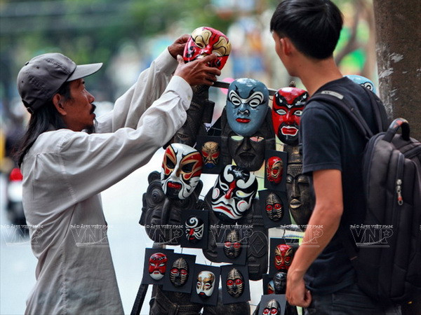 Ông Nguyễn Văn Bảy giới thiệu những chiếc mặt nạ hát bội với khách hàng. (Nguồn: Báo Ảnh Việt Nam)