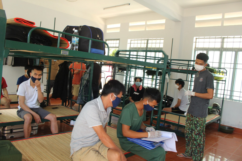 Hai chiến sỹ bộ đội tiến hành đo thân nhiệt định kỳ trong ngày cho các công dân Việt Nam trở về từ Hàn Quốc đang được cách ly tập trung 14 ngày. (Ảnh: Phan Sáu/TTXVN)