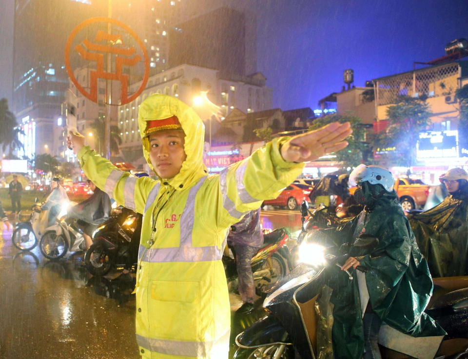 Cảnh sát giao thông Đội 1 (Công an Hà Nội) hướng dẫn giao thông tại ngã tư Cửa Nam trong buổi tối mưa rét. (Ảnh: Doãn Tấn/TTXVN)